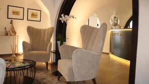 Un área de recepción con mostrador, dos sillones, una mesita con revistas y cuadros enmarcados en la pared.