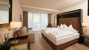 Una habitación de hotel con una cama grande, un sofá, un escritorio, una lámpara y una planta en maceta.