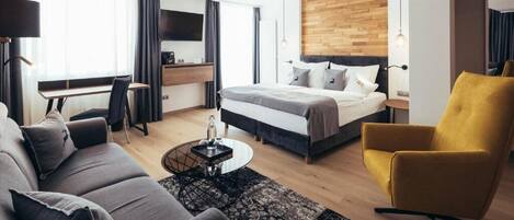 Una habitación de hotel moderna con cama, sofá, escritorio y un sillón amarillo.