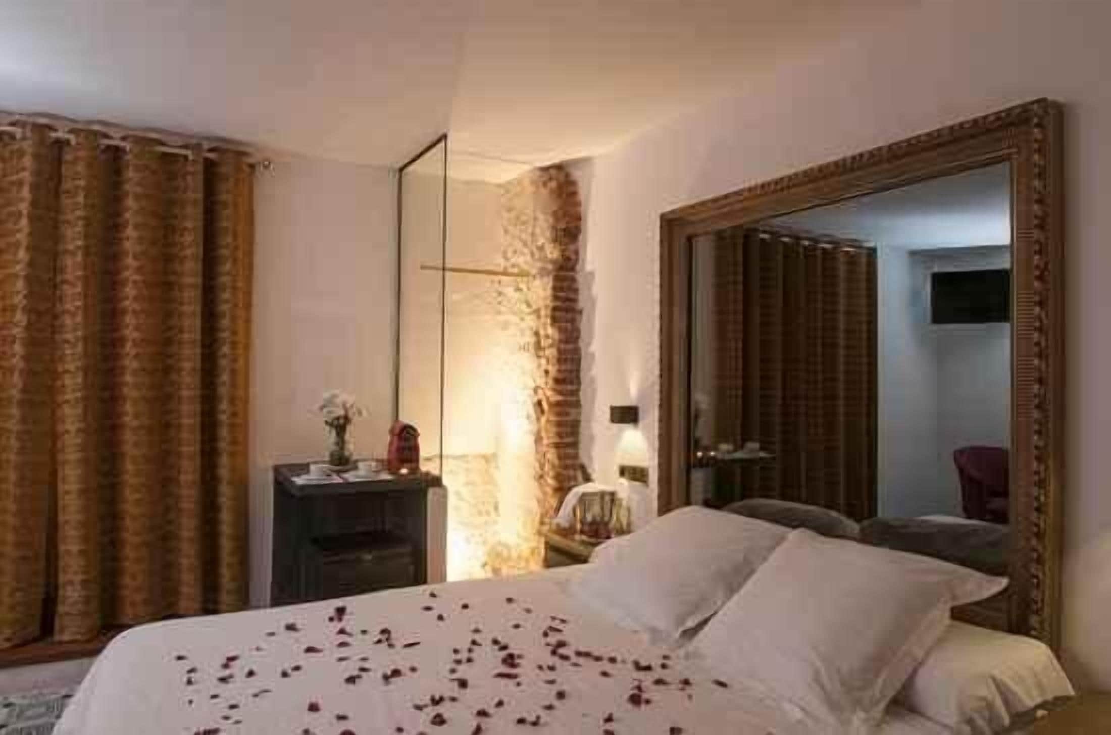 Una habitación de hotel con una cama grande, un espejo, una mesita de noche y una pared de ladrillo.