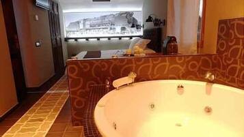 A bathroom with a large bathtub, a shower area, and a view of a cityscape through a window.