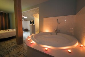 Un baño moderno con una bañera independiente, ducha y una pequeña zona de estar.