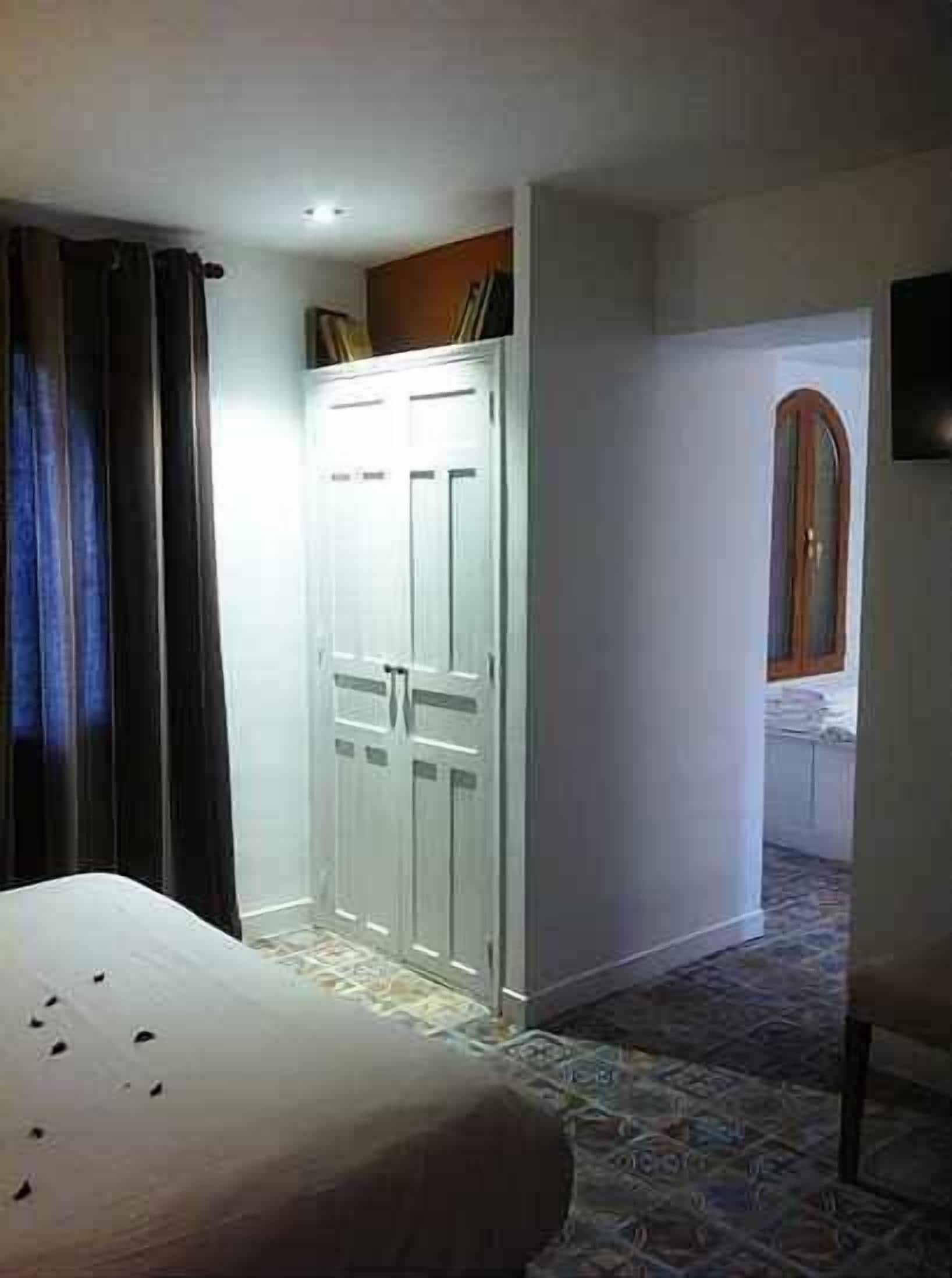 Un dormitorio con cama, armario y baño visible a través de una puerta abierta.