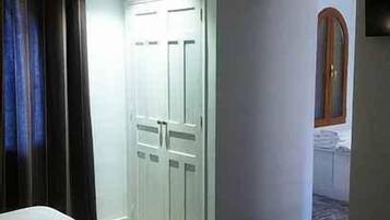 Un dormitorio con cama, armario y baño visible a través de una puerta abierta.