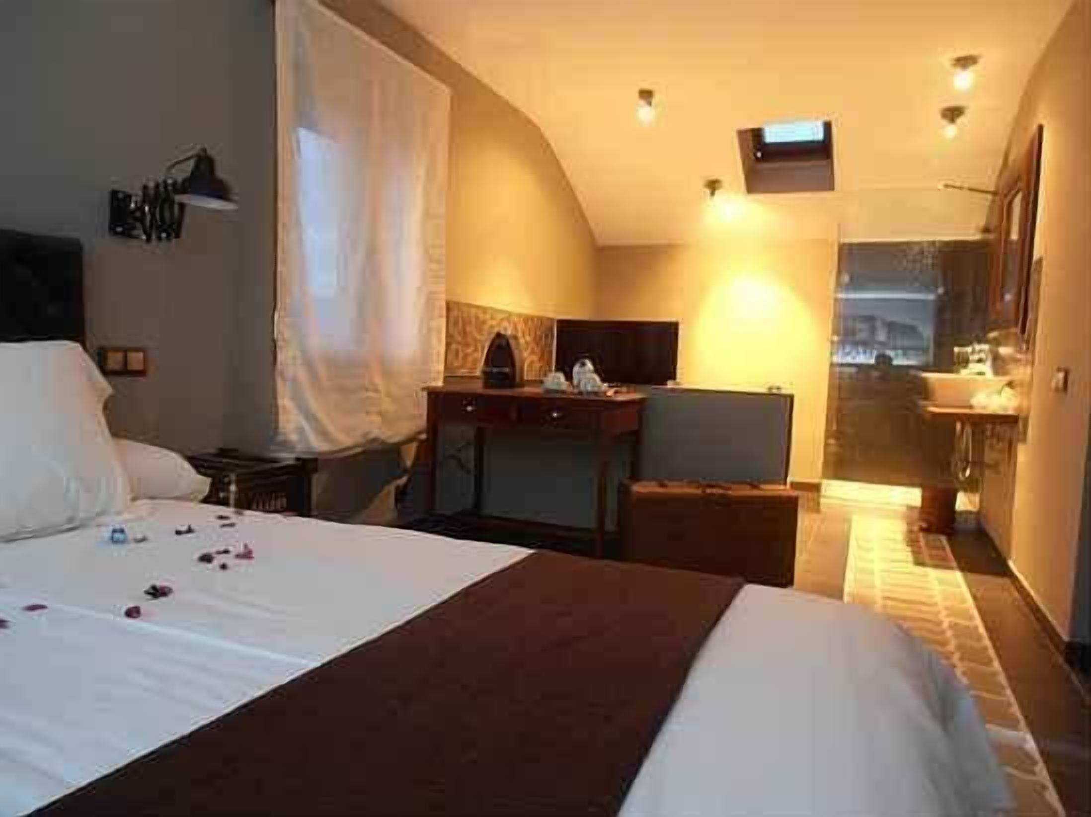 Habitación de hotel con cama, escritorio, silla, televisor y baño visible a través de una puerta abierta.