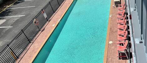 A rectangular pool with a brick deck and a metal railing.