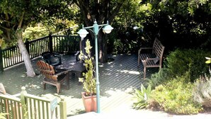 A wooden deck with a railing, surrounded by greenery. - Carmel Guest Farm (Wilderness)