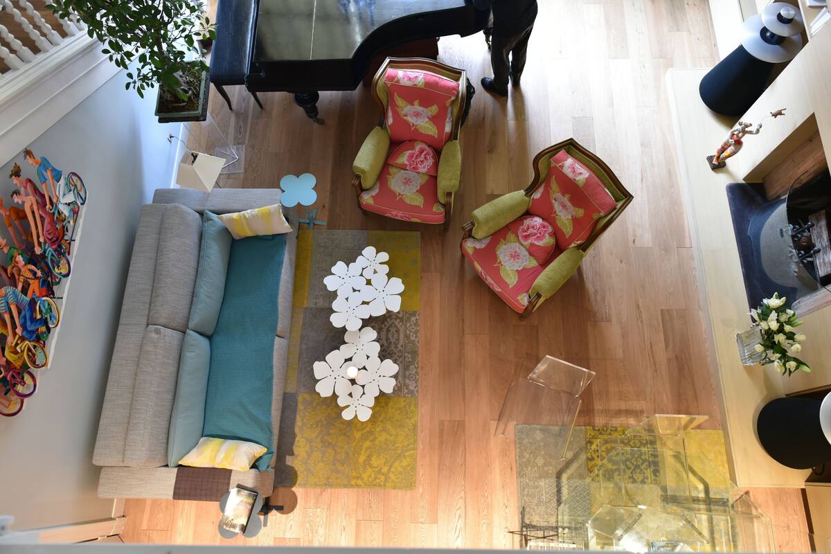 A living room with a gray sofa, two floral armchairs, a coffee table, and a piano.