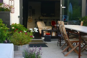 An outdoor patio with a dining table, chairs, and a guitar in the background.