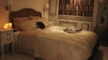Une chambre avec un grand lit, une table de chevet avec une lampe et une bibliothèque en arrière-plan.