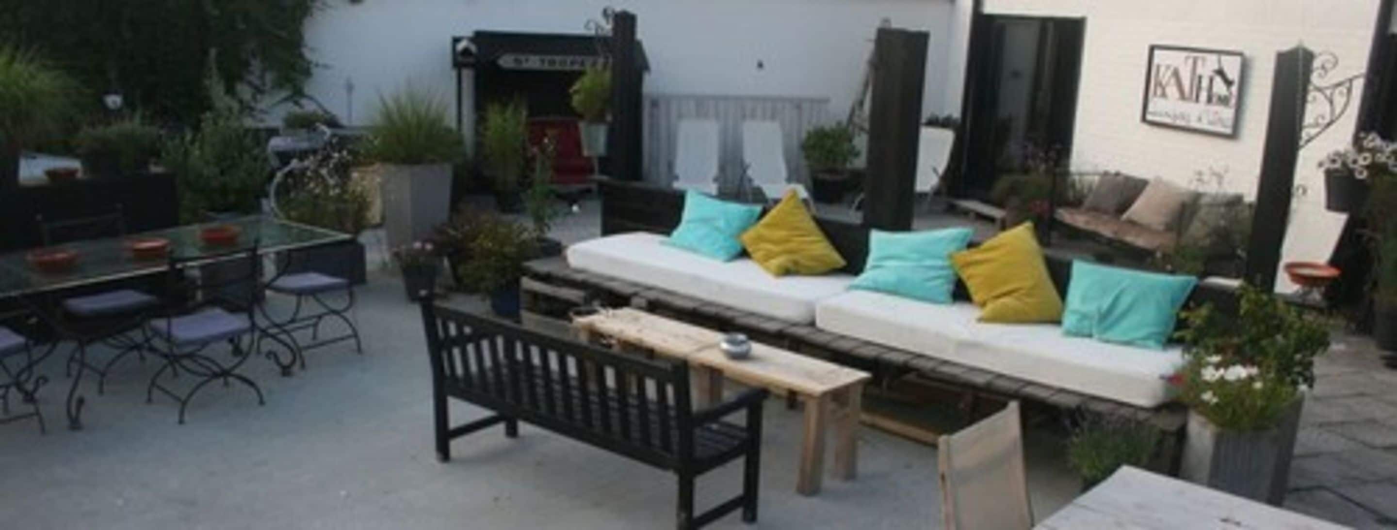Un espacio al aire libre con patio, sofá, mesa de comedor y sillas.