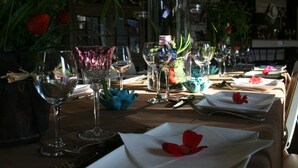 A dining table set with wine glasses, plates, and a centerpiece of flowers and greenery. - Kathome (Bondues)