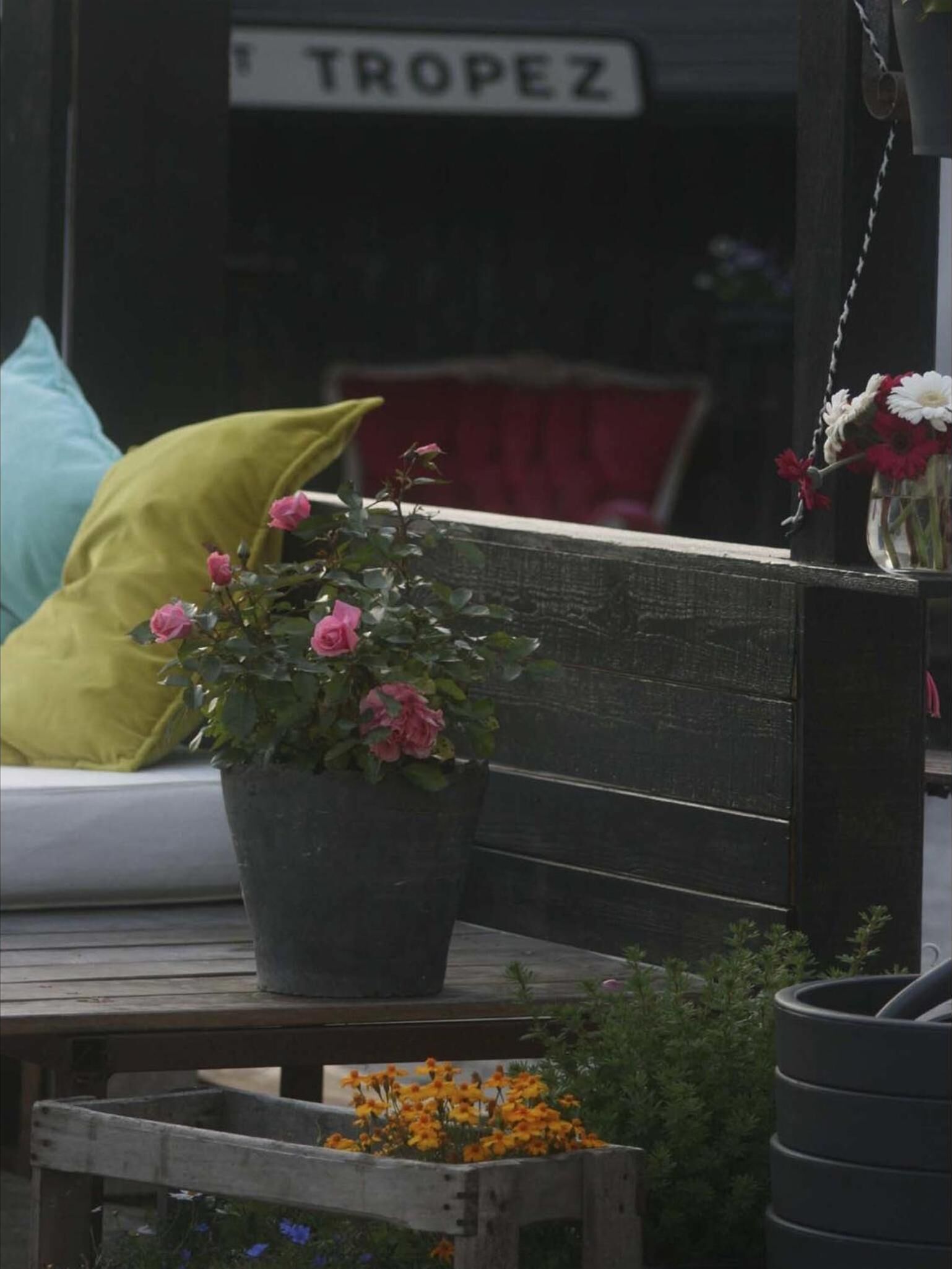 A wooden bench with a potted plant and flowers.