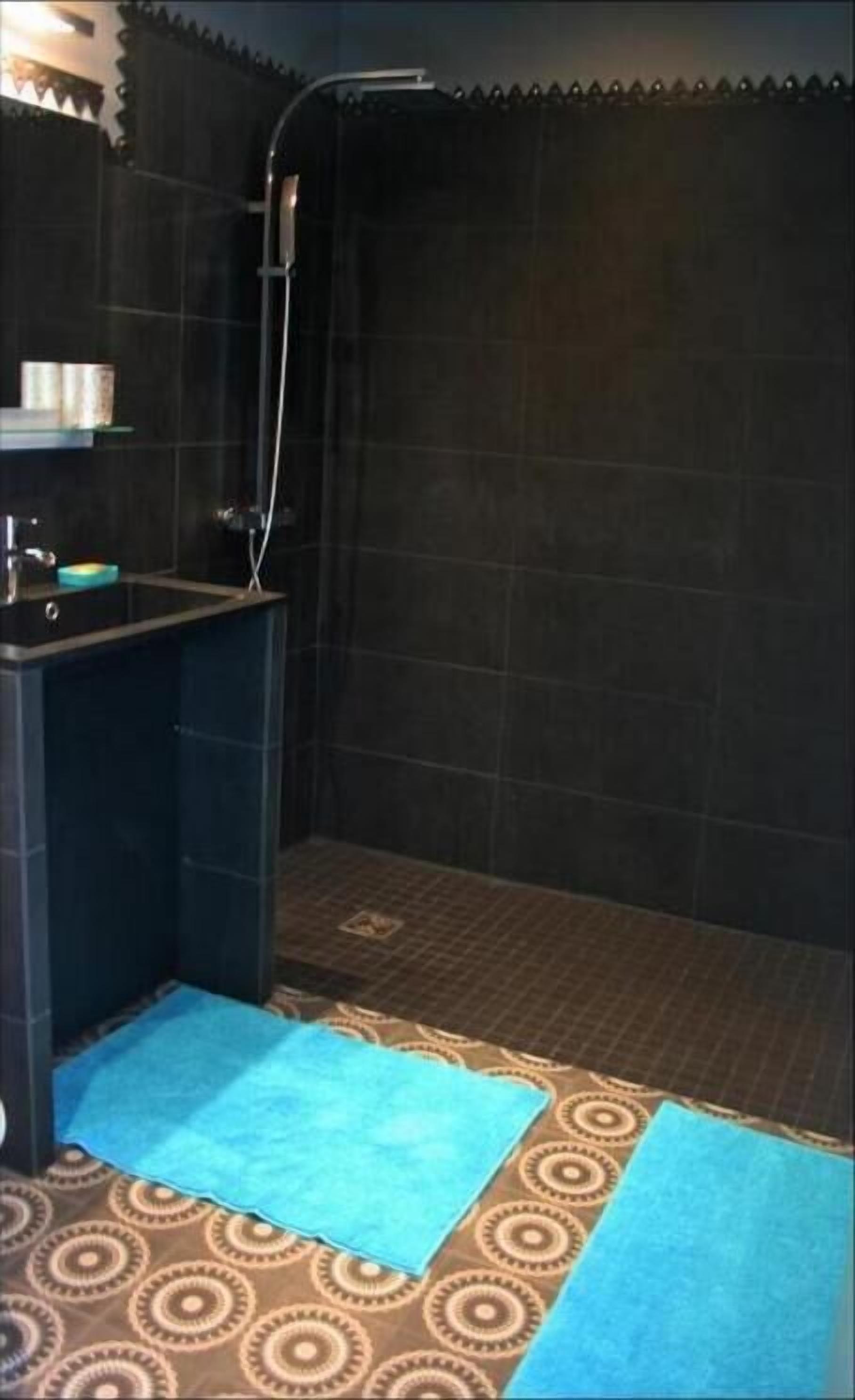 A small bathroom with a shower, a sink, and a patterned floor.