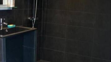 A small bathroom with a shower, a sink, and a patterned floor.