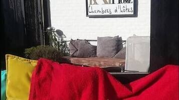 A dog lying on a red blanket in a room with a white wall and a sign that reads "KATHOME Chambres d'hôtes".