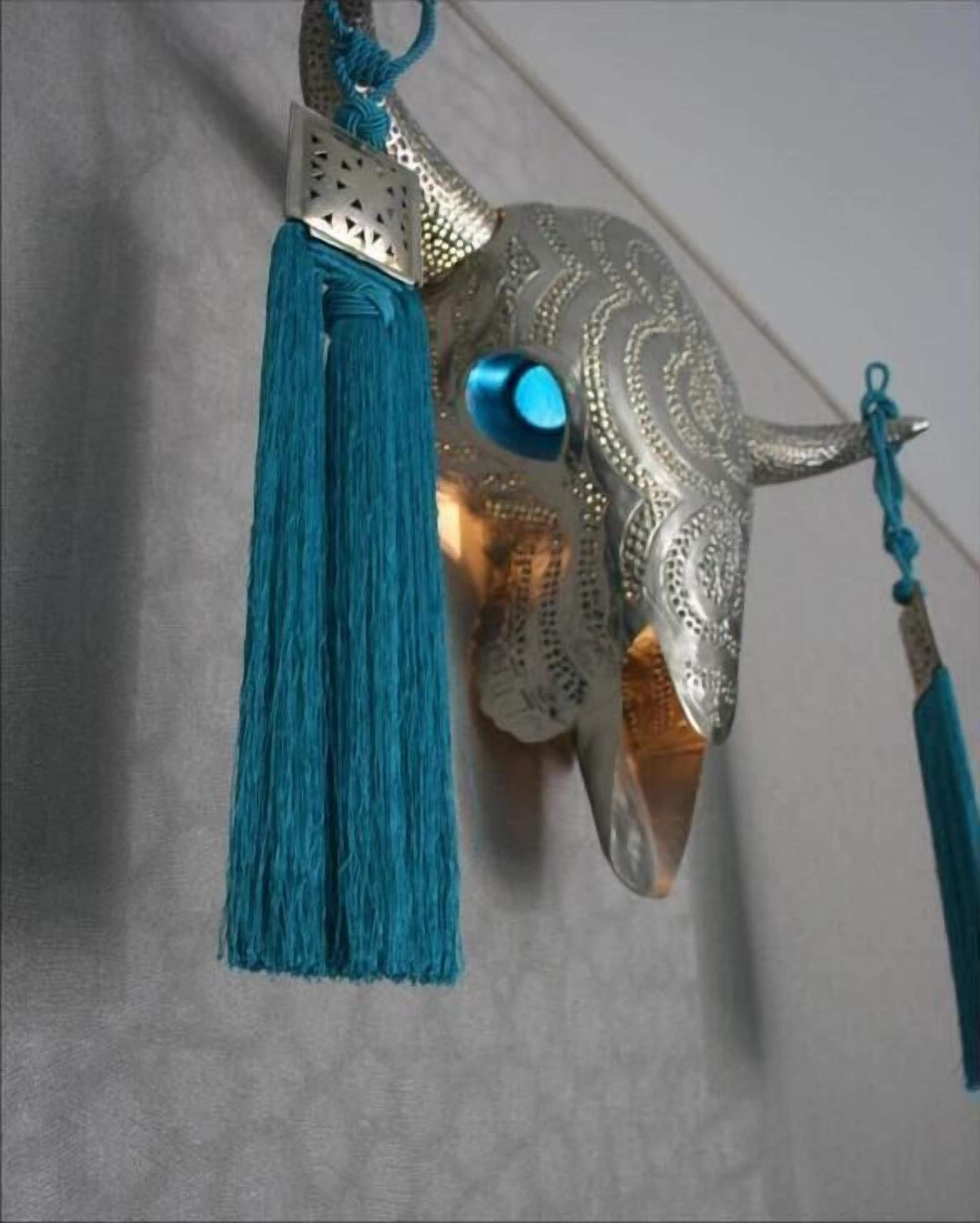 Une sculpture décorative en métal, ornée d’une pompon bleu.