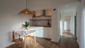 A modern kitchen with a round dining table, wooden chairs, and a hanging light fixture. -  Carmo Country Villas (Ponta Delgada)