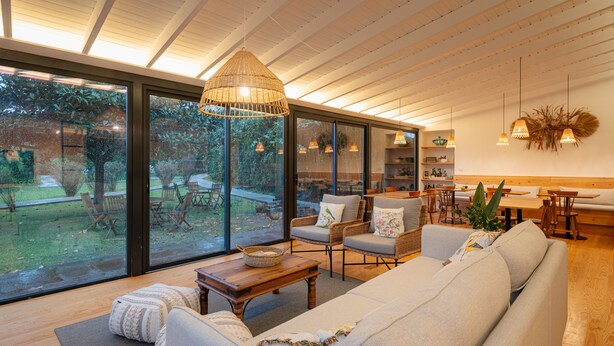 A spacious living area with a large sofa, wooden coffee table, and wicker pendant lights. -  Carmo Country Villas (Ponta Delgada)