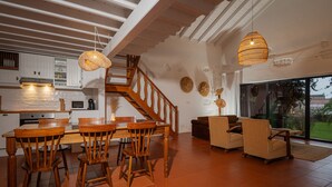 A spacious kitchen with wooden furniture, a staircase, and large windows. -  Carmo Country Villas (Ponta Delgada)