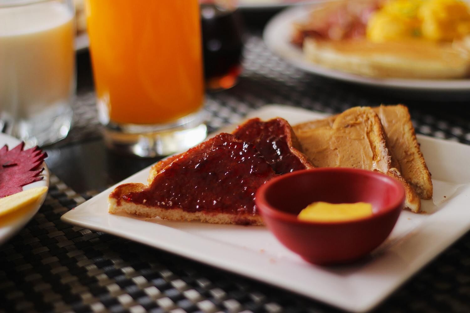 Un piatto per la colazione con pane tostato, marmellata e una piccola ciotola di burro.