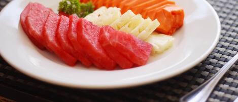 A plate of sliced watermelon, cantaloupe, and honeydew melon on a table with a woven placemat.