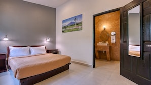 A bedroom with a bed, bedside lamps, a painting, a bathroom with a mirror, sink, and towel rack. - Wayak Hotel & Suites (Managua)