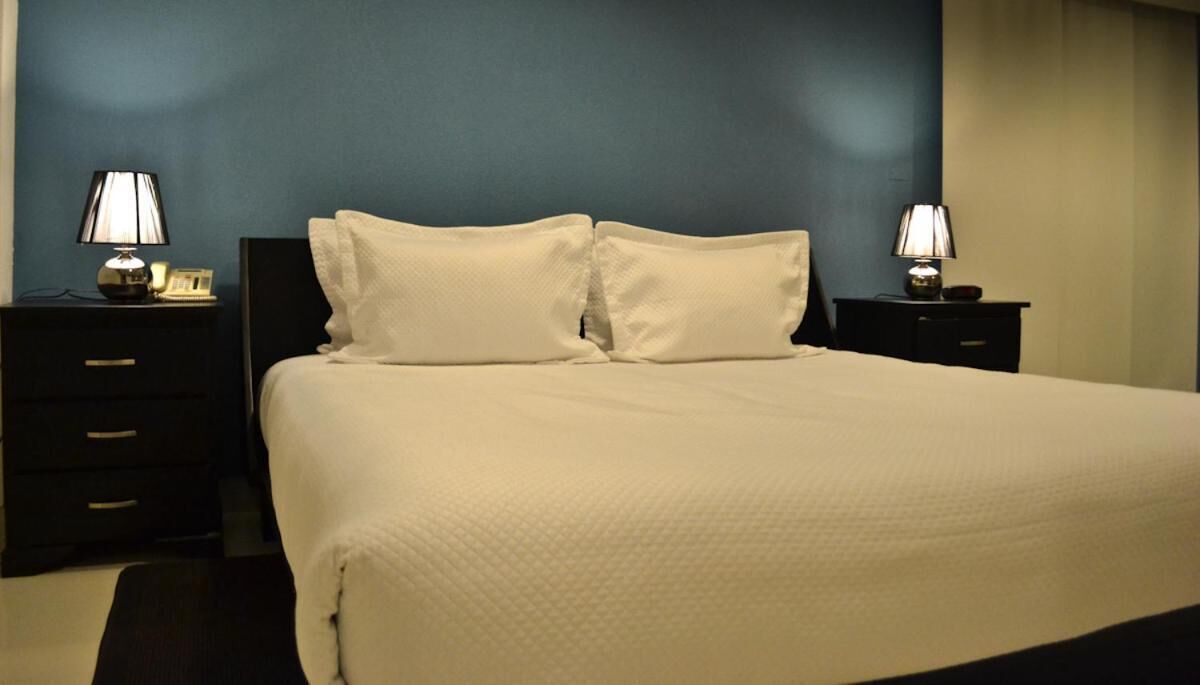 Una cama bien hecha con ropa blanca en una habitación de paredes azul oscuro.