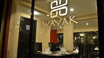 Un restaurante con un muro de cristal que muestra el logotipo del Wayak Hotel & Suites.