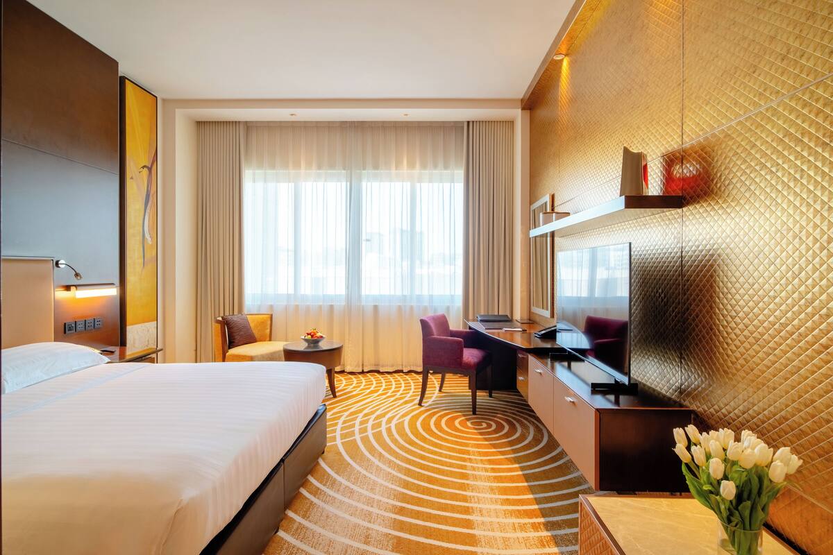 Ein Hotelzimmer mit einem großen Bett, einem Schreibtisch mit Stuhl, einem Fernseher und einer Wanddekoration.