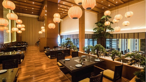 Ein Restaurant mit Holzböden, gedeckten Tischen und hängenden Papierlanterndosen.