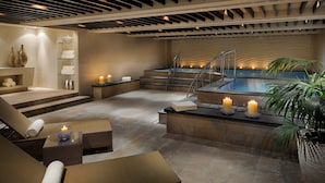 Ein moderner Wellnessbereich mit Pool, Liegestühlen und einer Treppe zu einer Hot Whirlpool.