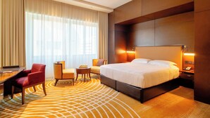 Ein Hotelzimmer mit einem großen Bett, einem Schreibtisch, einem Stuhl und einem kleinen Tisch.