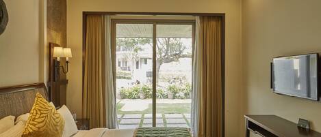 A hotel room with a bed, a desk, a television, and a view of the outdoors.