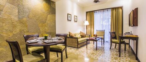 A dining area with a stone accent wall, a round table with chairs, and a sofa with cushions.