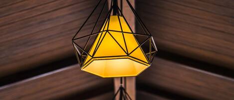 A series of geometric pendant lights with a warm yellow glow, hanging from a wooden ceiling structure.