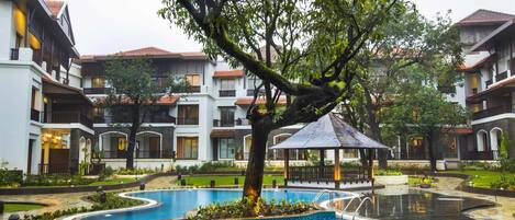 A courtyard with a swimming pool, surrounded by multi-story buildings with balconies and a gazebo.