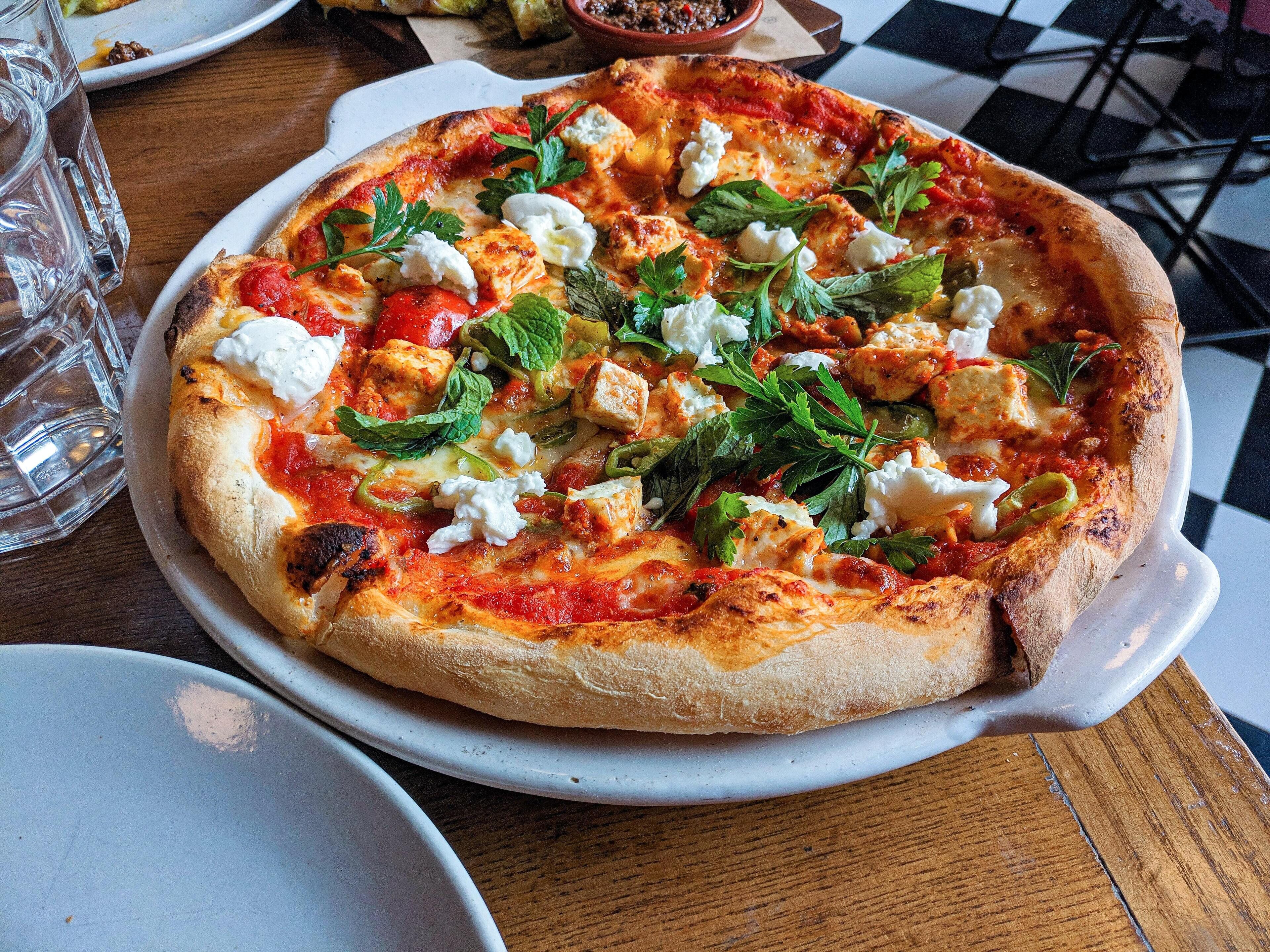 Una pizza con diferentes ingredientes sobre un plato blanco.