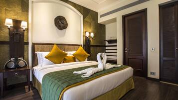 A hotel room with a large bed, two bedside lamps, a clock on the wall, and a door with a louvered design.