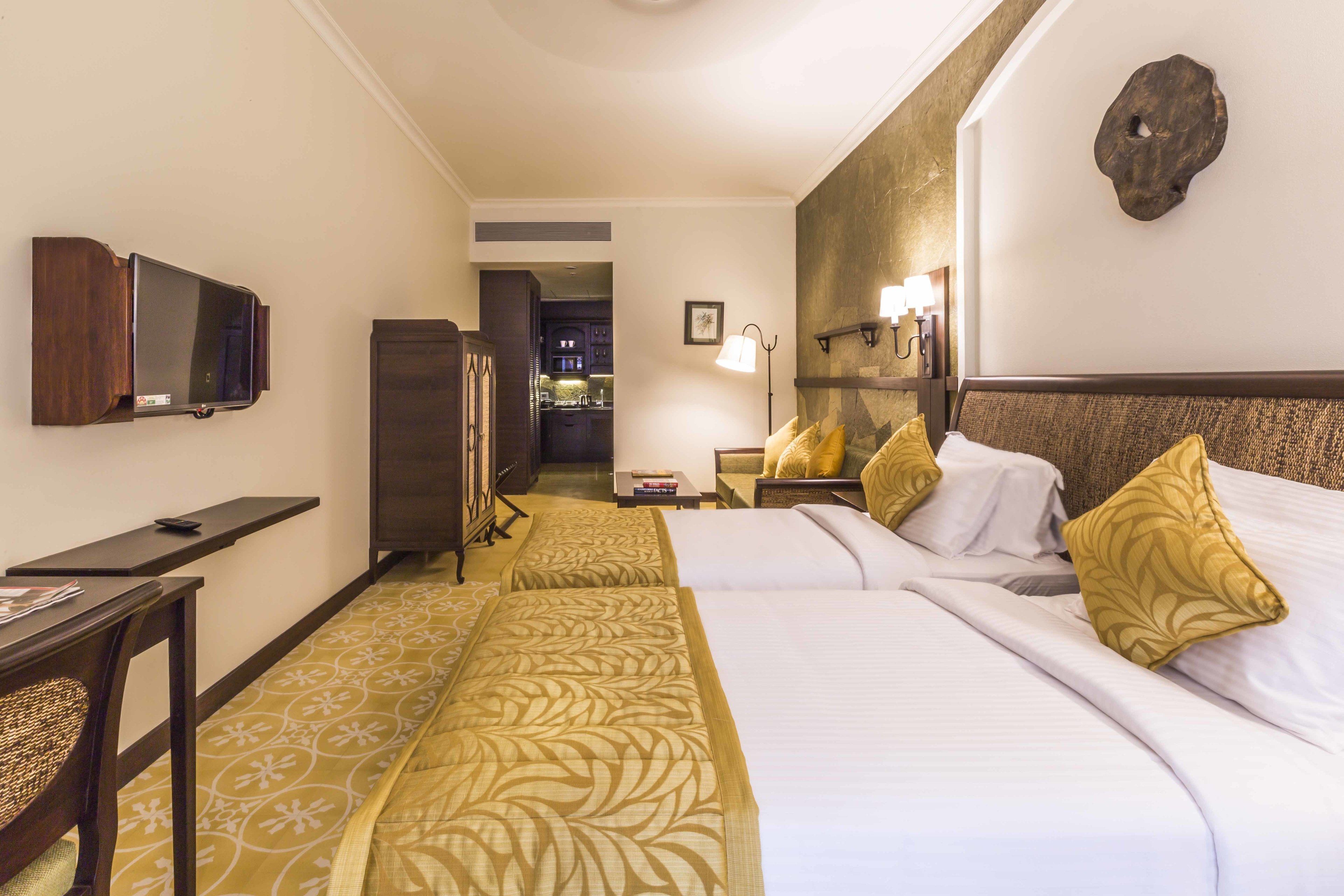 A hotel room with two beds, a desk, a TV, and a bathroom visible through an open door.