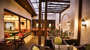 Un espacio interior con asientos de mimbre, un separador de vidrio y vista a la habitación contigua.