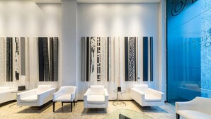 Un interior moderno con sofás blancos, una mesa de centro de vidrio y arte mural con diseños.
