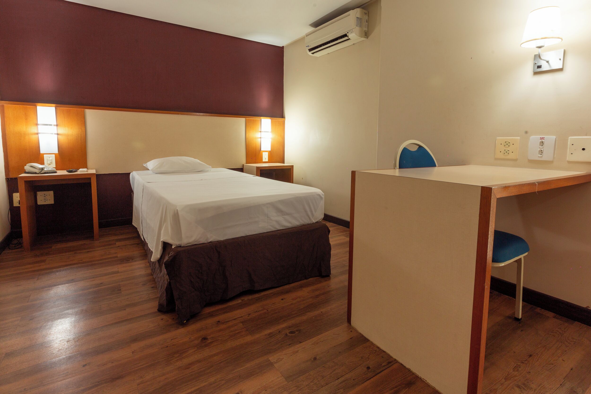Une chambre d’hôtel avec un lit, des tables de chevet, un bureau et une chaise.