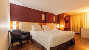 Una habitación de hotel con una cama, una silla, un escritorio y un armario.