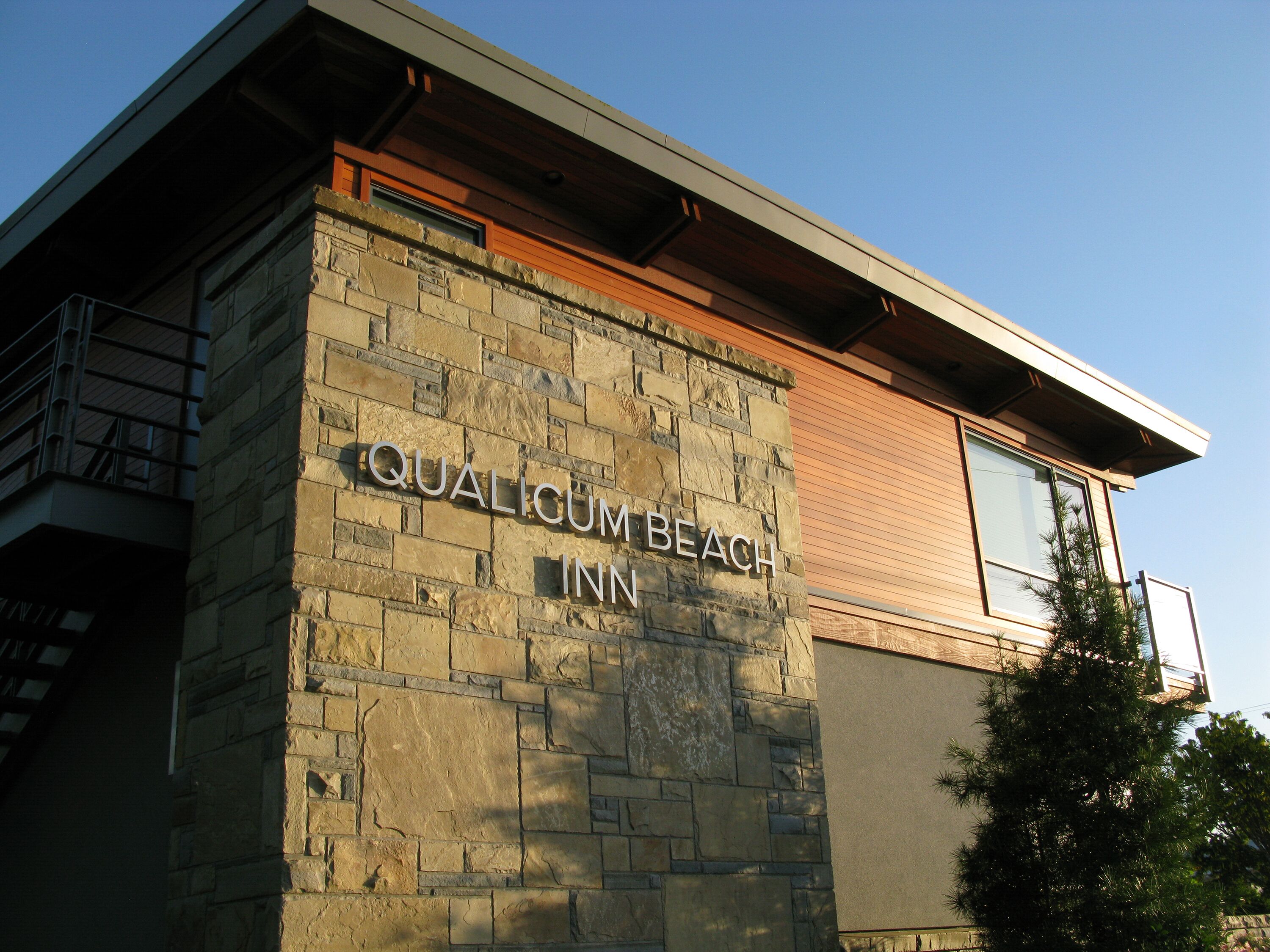 A building with a stone facade and a sign that reads "QUALICUM BEACH INN".