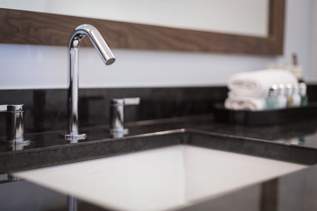 Un bagno moderno con un lavandino capiente, uno specchio e un portascopino.