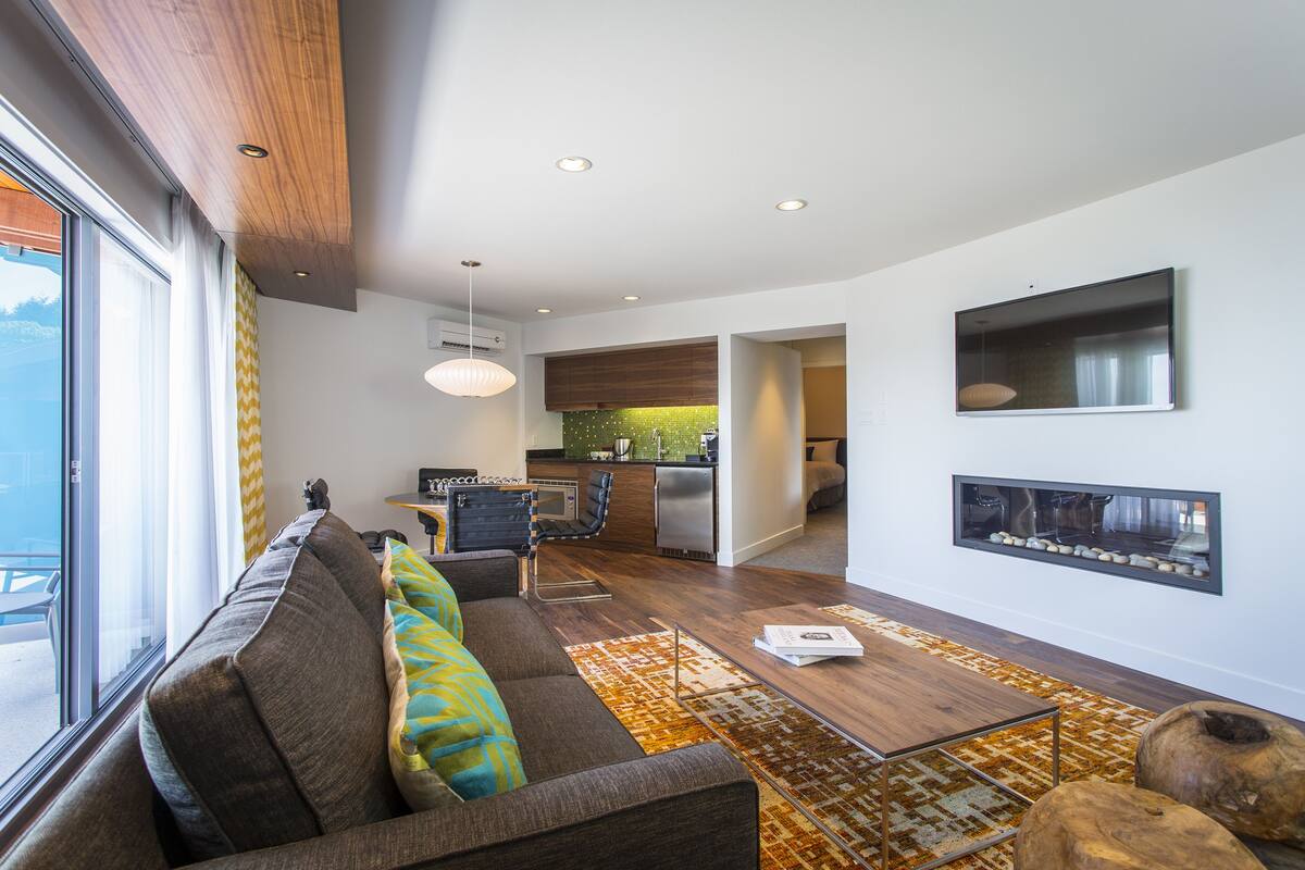 Una sala de estar moderna con un sofá, una mesa de centro y una cocina al fondo.