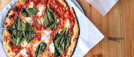Two pizzas on wooden tables with pizza paper.