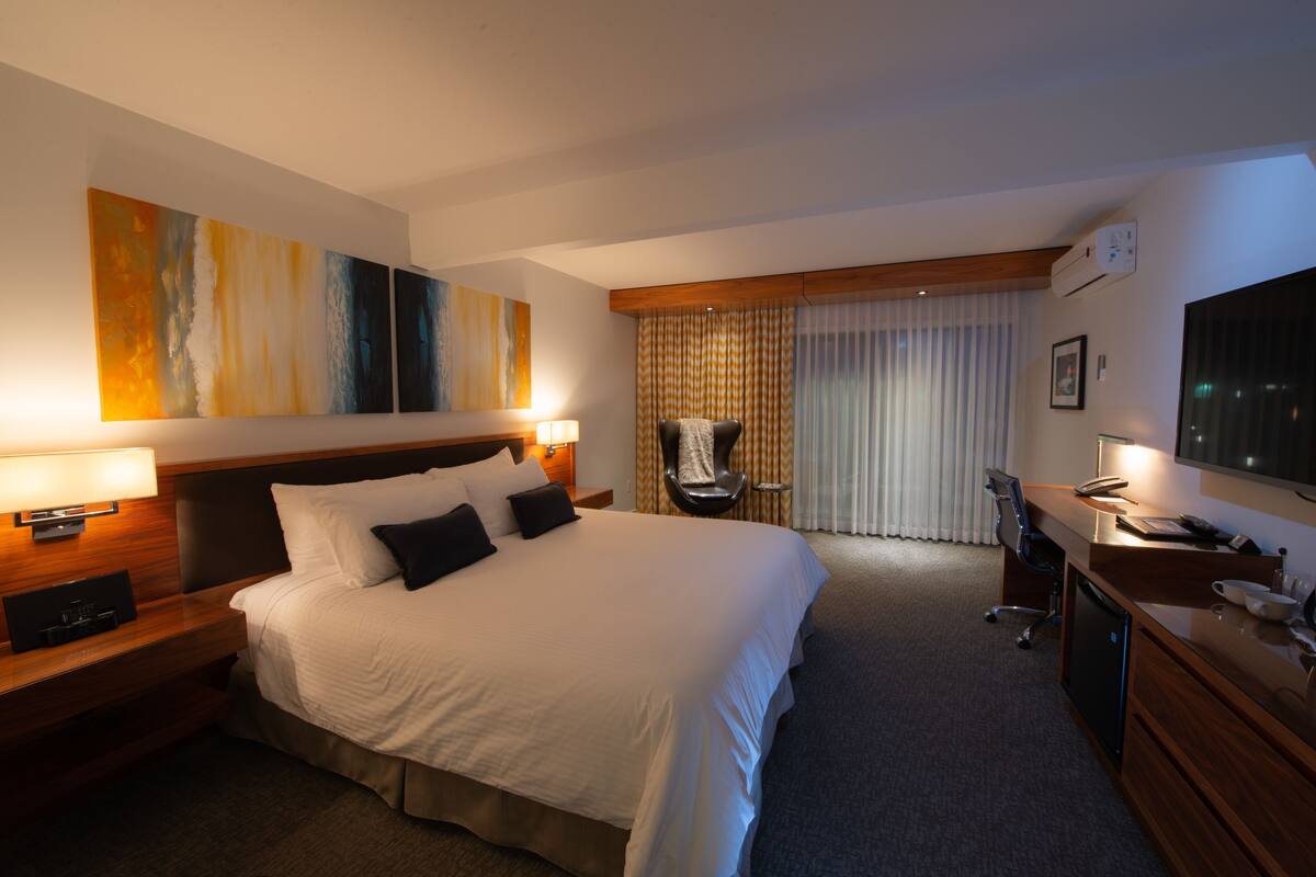 Una habitación de hotel con una cama grande, mesitas de noche, un escritorio, una silla y una televisión.
