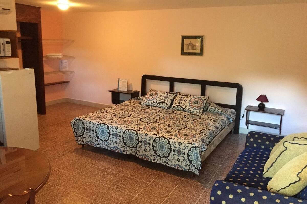 Un dormitorio con una cama, una mesita de noche, una silla y una pequeña mesa.
